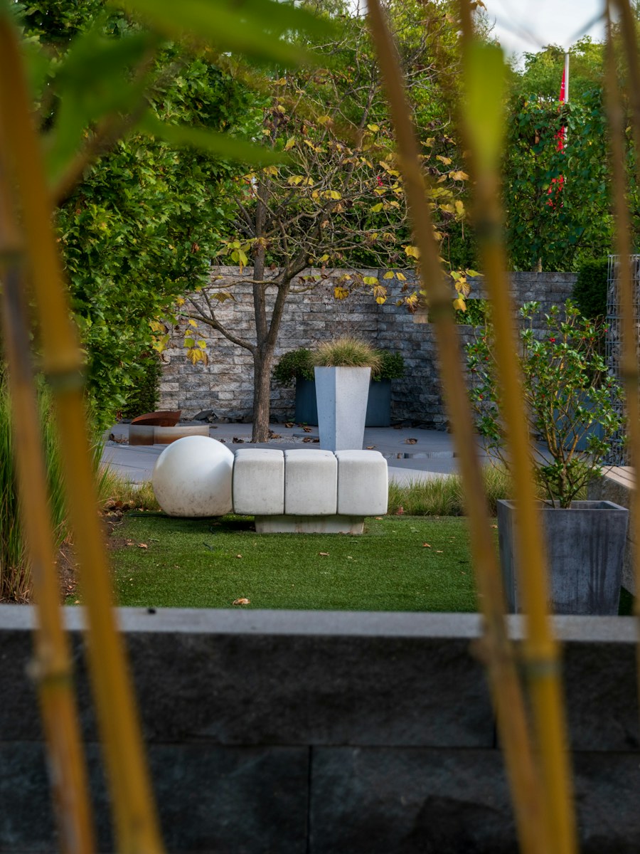 Jardín diseñado con muro de piedra, banco escultórico y plantación estructurada